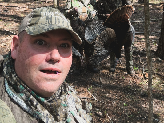 a turkey hunter standing in front of two longbeard turkeys